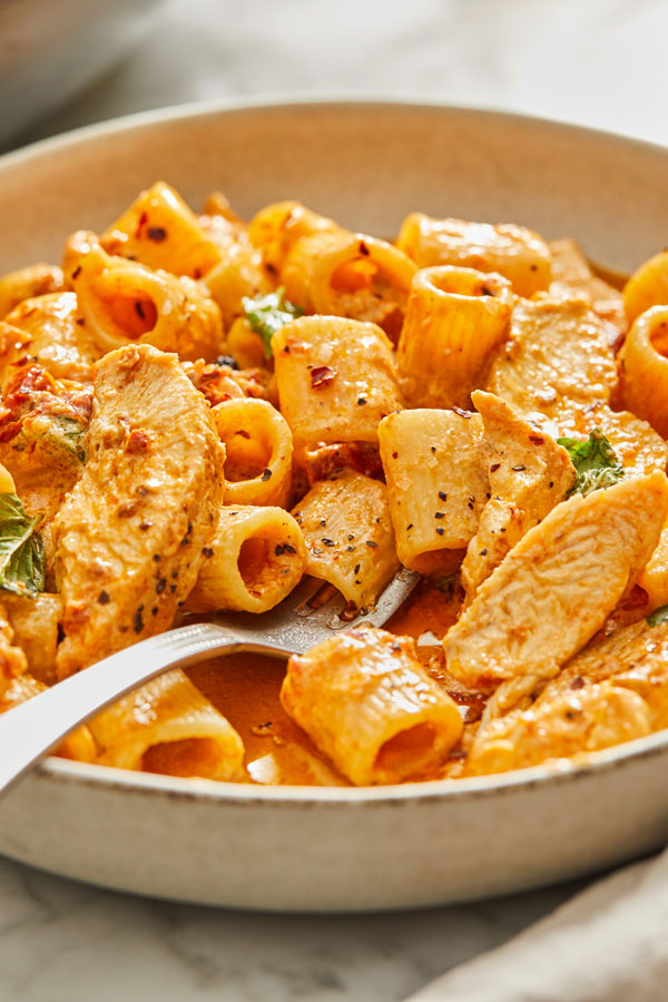 Pasta in a bowl with chicken in a red sauce