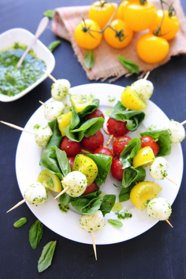 Pesto Caprese Salad with mozzarella, tomatoes, and basil leaves. 